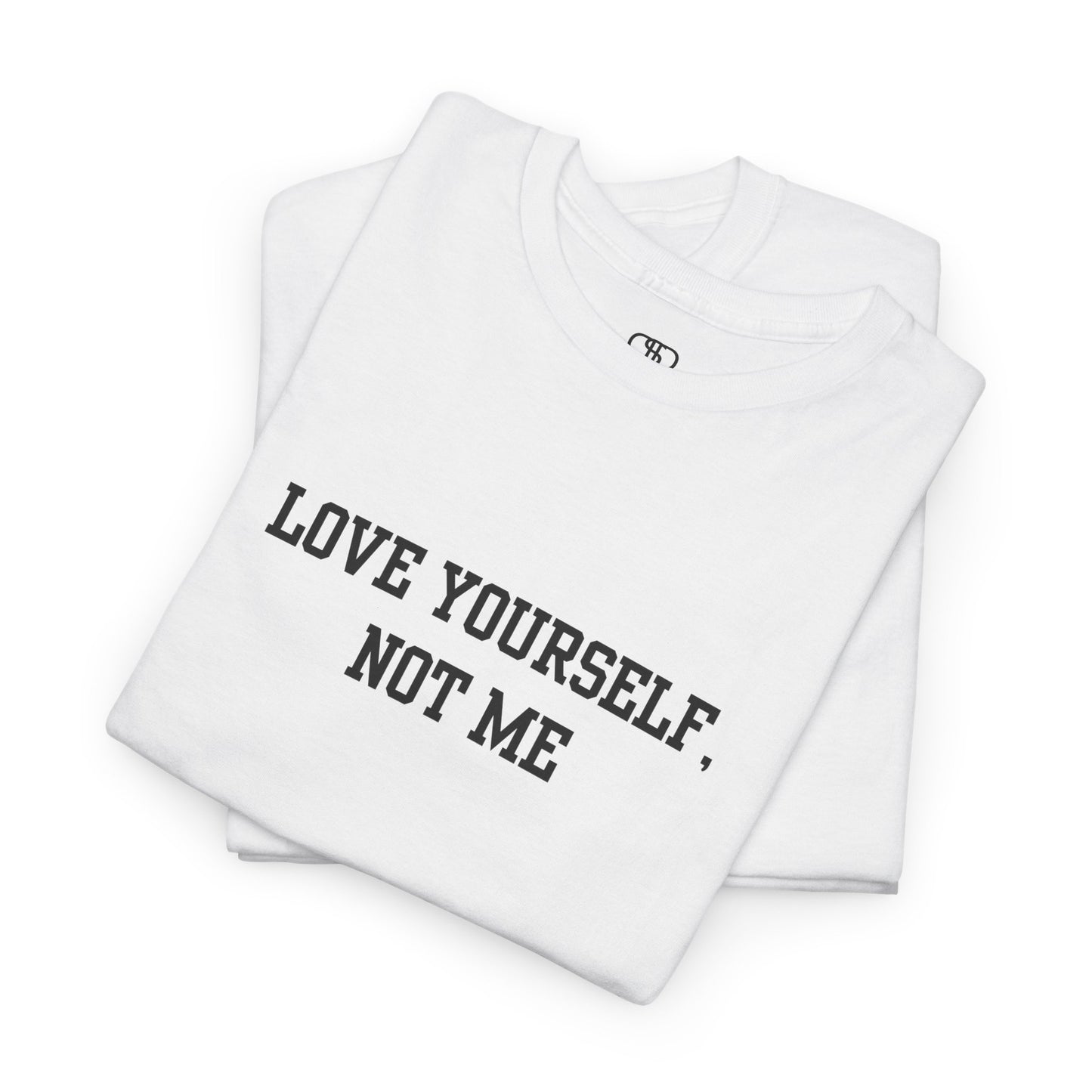 A folded minimalist t-shirt with the bold, centered text "Love yourself, not me" in a clean, modern font.