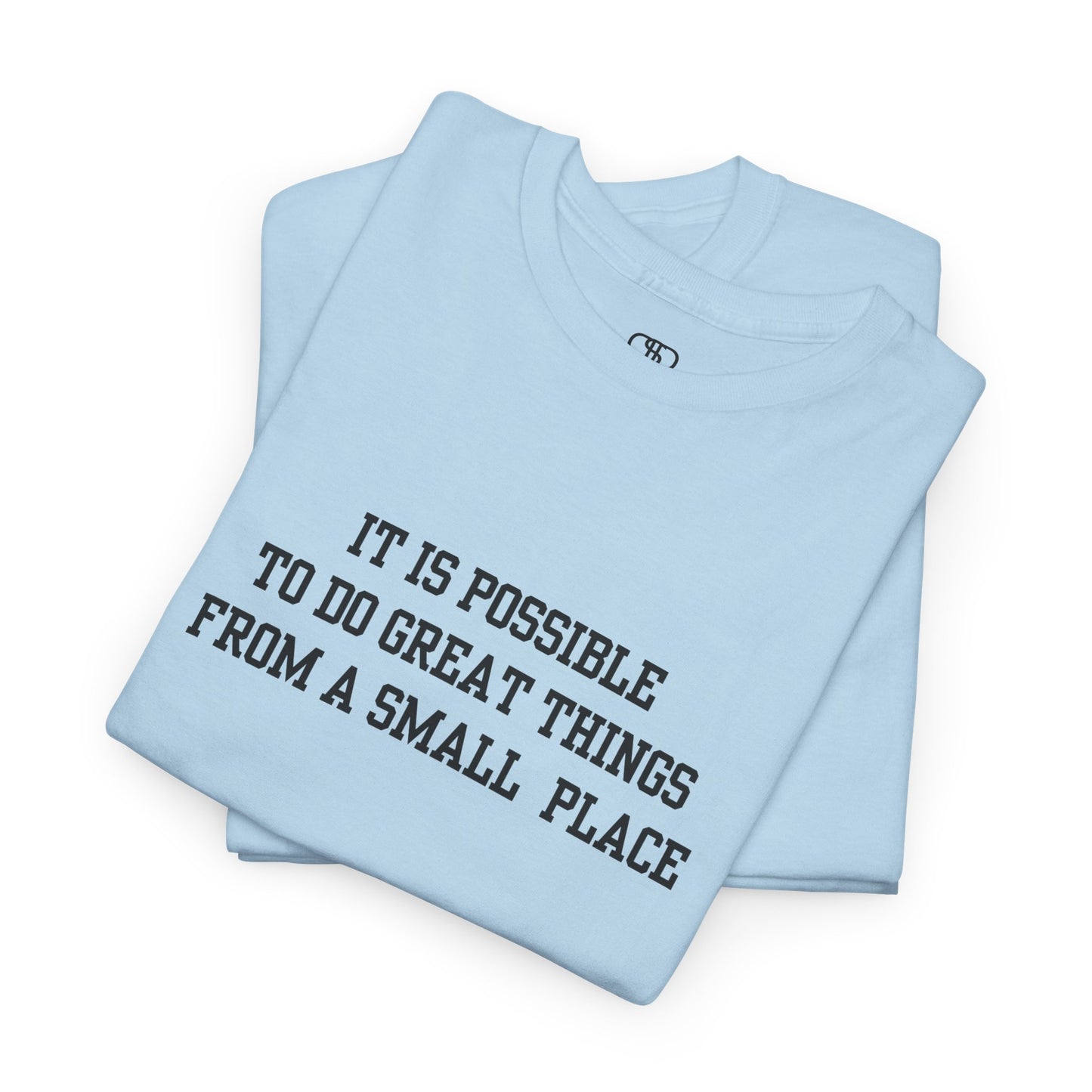 A folded light blue t-shirt with the quote “It is possible to do great things from a small place” on the front.
