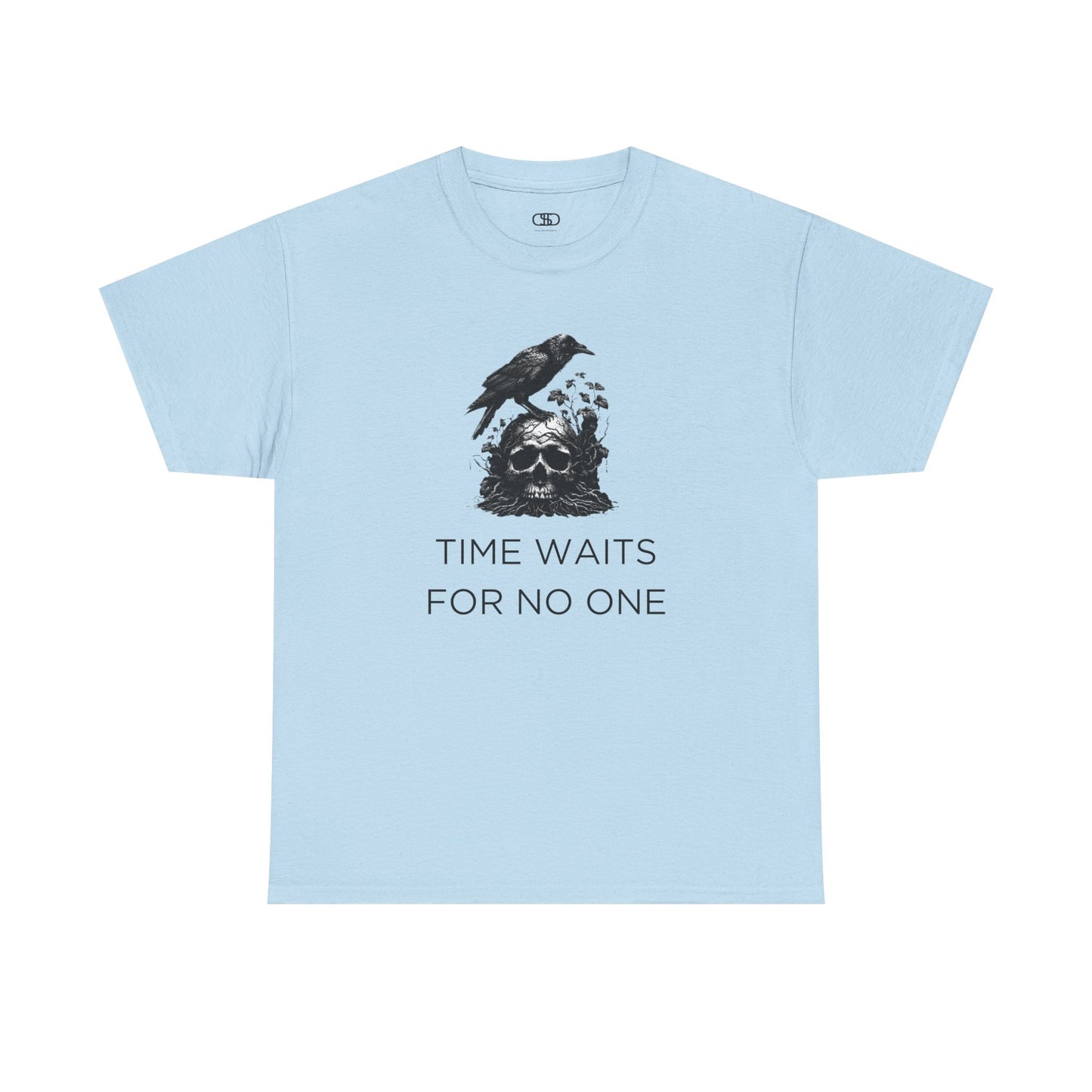 A close-up of a t-shirt with a gothic illustration. A black crow stands atop a weathered skull, which has moss and delicate vines growing through its eye sockets and around its form, blending nature and death.