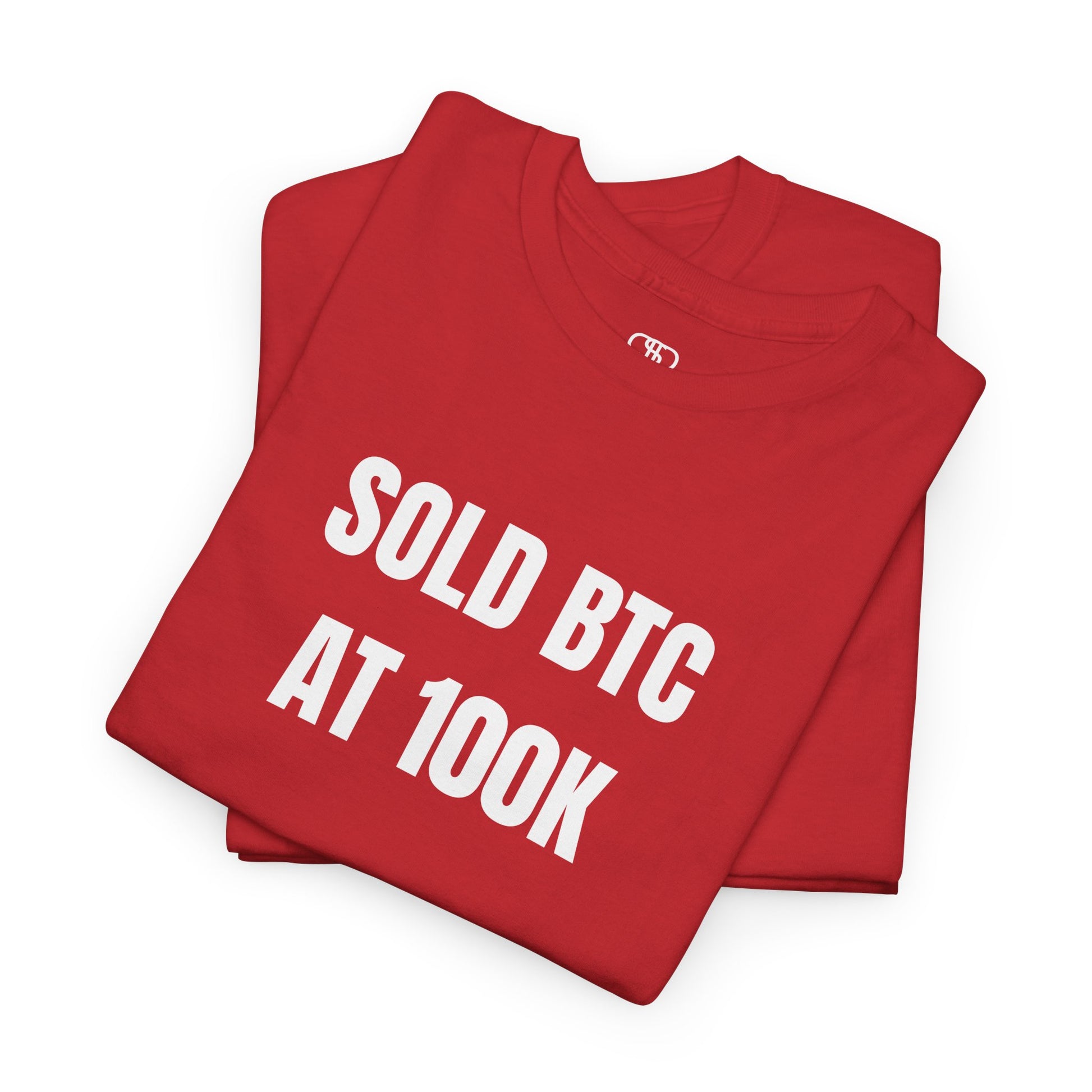 A folded red T-shirt with bold text "SOLD BTC At 100K" on the front.