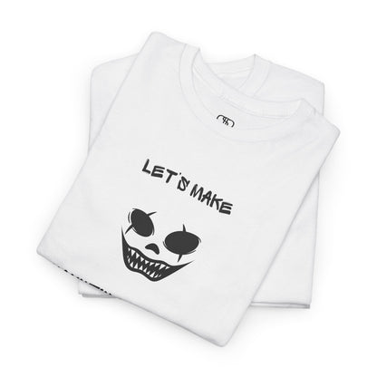 A folded white T-shirt with a daring clown graphic with sharp teeth and scars, and "Let’s Make Haunting Memories" text.