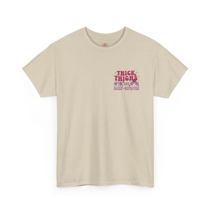 A [sand] t-shirt with the phrase "Thick Thighs and Sleep Deprived" in a retro font on the front left and enlarged on the back.