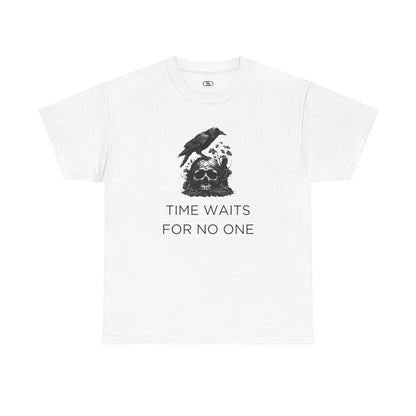 A close-up of a t-shirt with a gothic illustration. A black crow stands atop a weathered skull, which has moss and delicate vines growing through its eye sockets and around its form, blending nature and death.