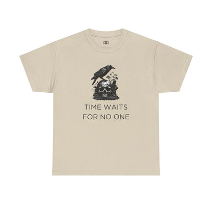 A close-up of a t-shirt with a gothic illustration. A black crow stands atop a weathered skull, which has moss and delicate vines growing through its eye sockets and around its form, blending nature and death.