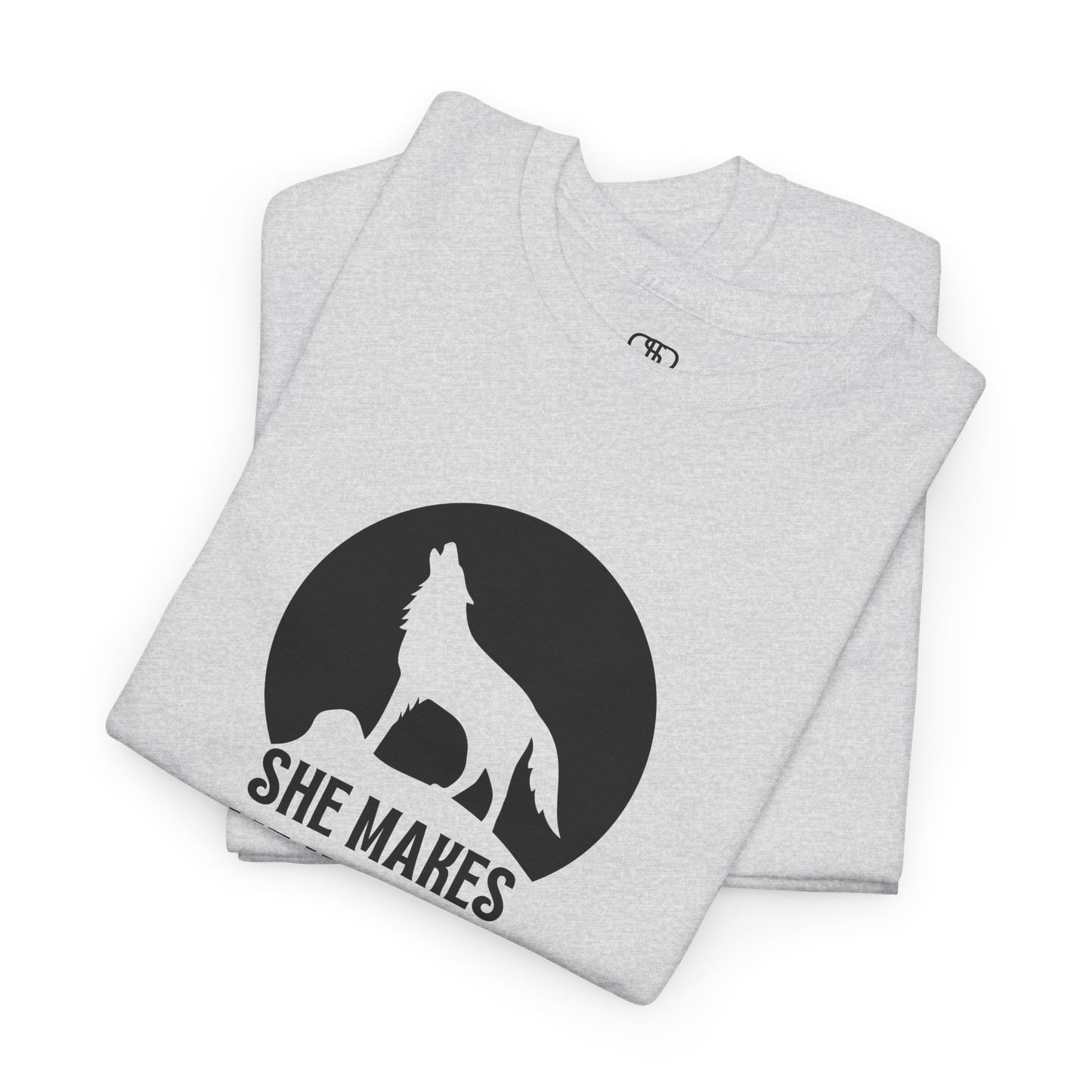 A folded ash gray T-shirt with a wolf silhouette howling at the moon on a cliff, and "She makes me HOOWWL" text.