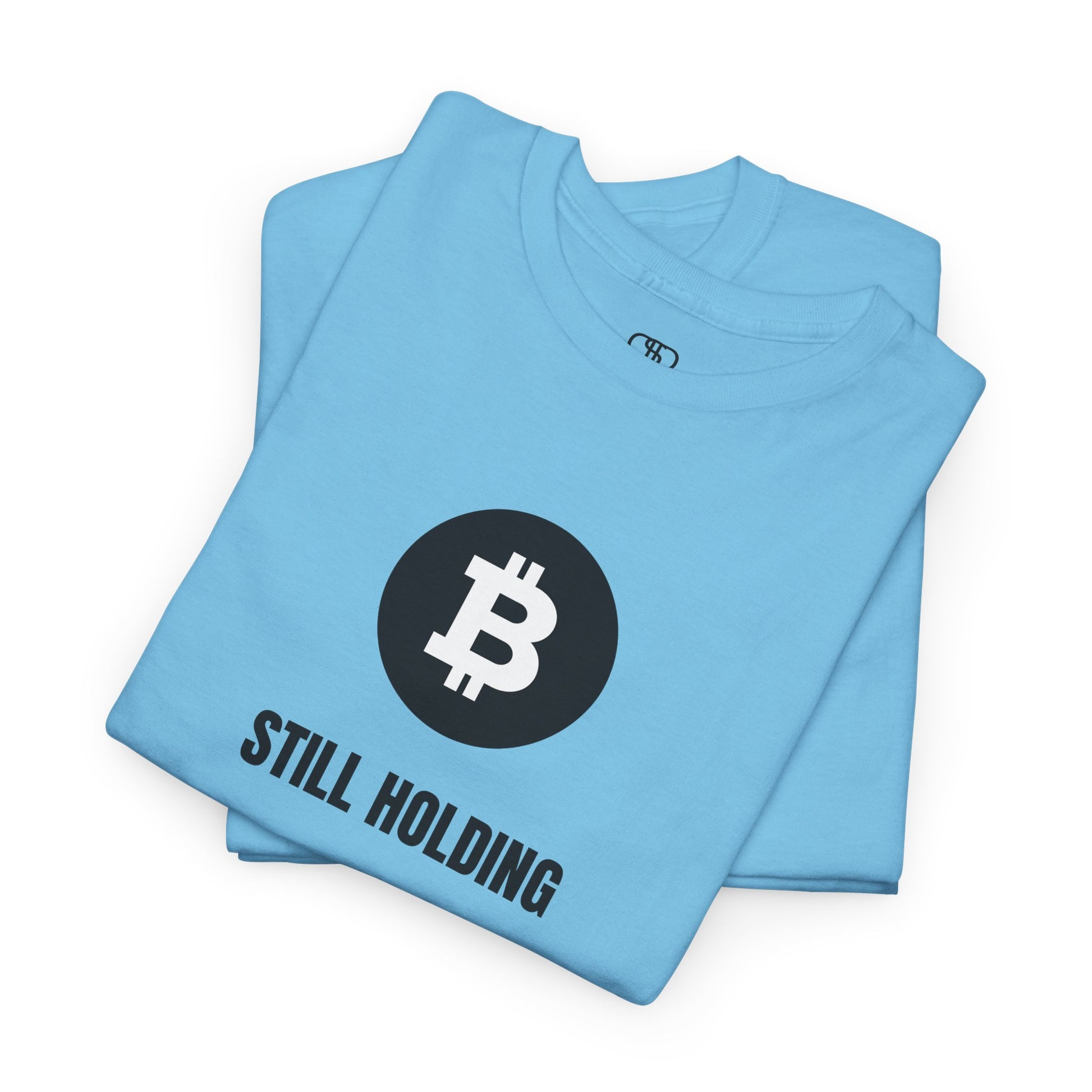 A folded sky blue T-shirt with a Bitcoin emblem and "Still Holding" text in black.