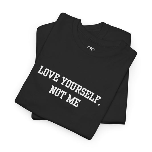 A minimalist folded t-shirt with the bold, centered text "Love yourself, not me" in a clean, modern font.