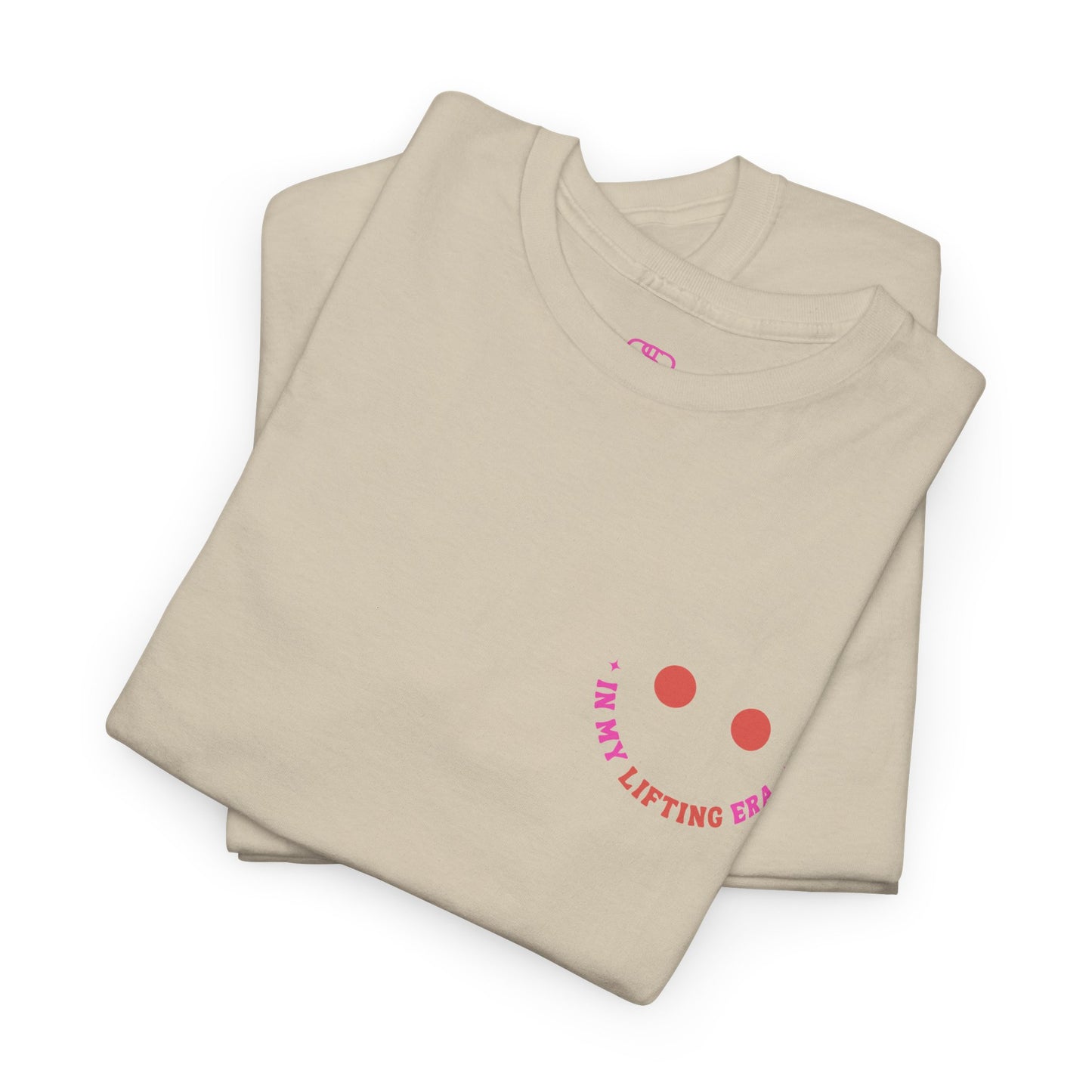A folded sand  t-shirt with a retro smiley face on the front and the phrase “In my lifting Era” in a creative retro design on the back.