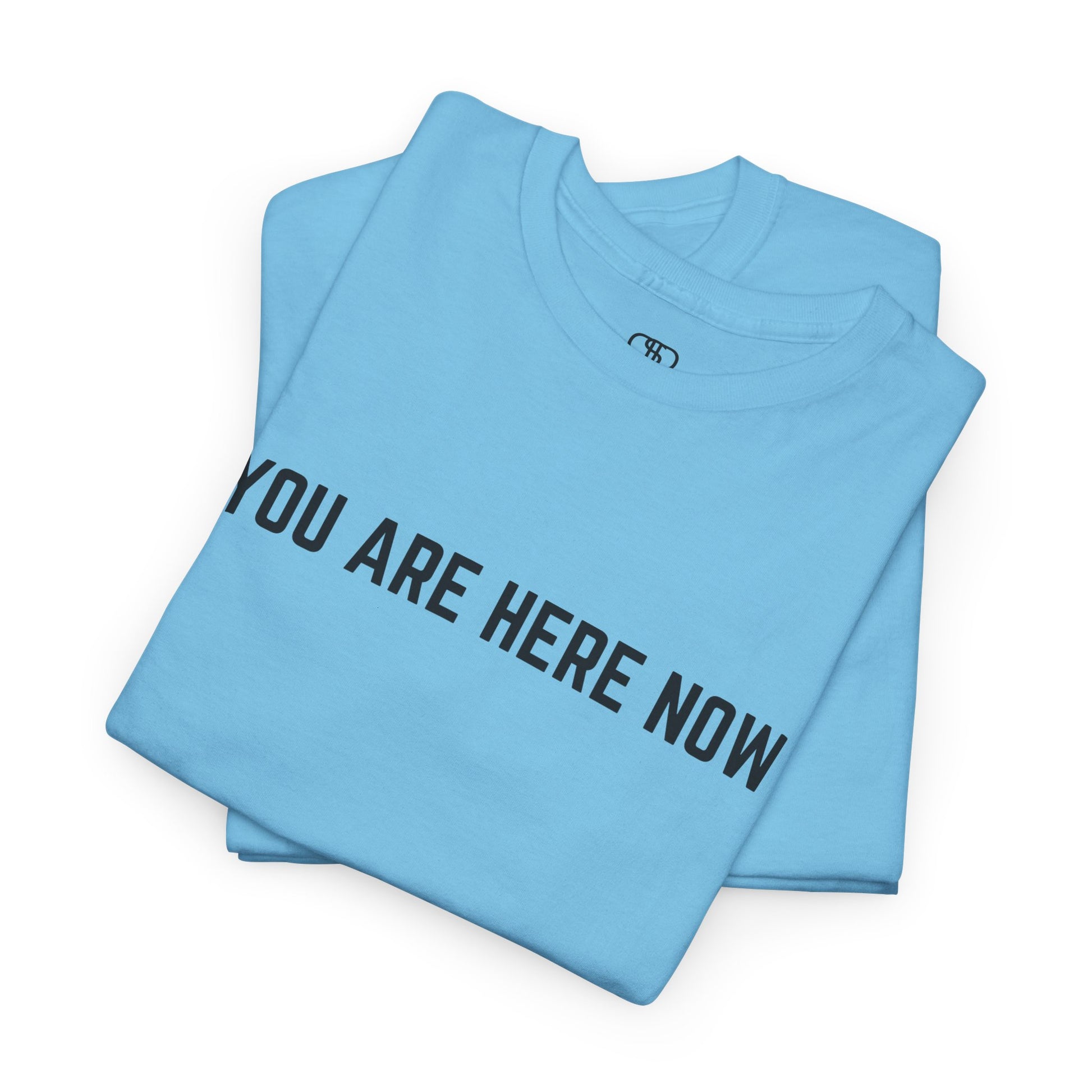 A folded sky t-shirt with the words "You are Here Now." 
