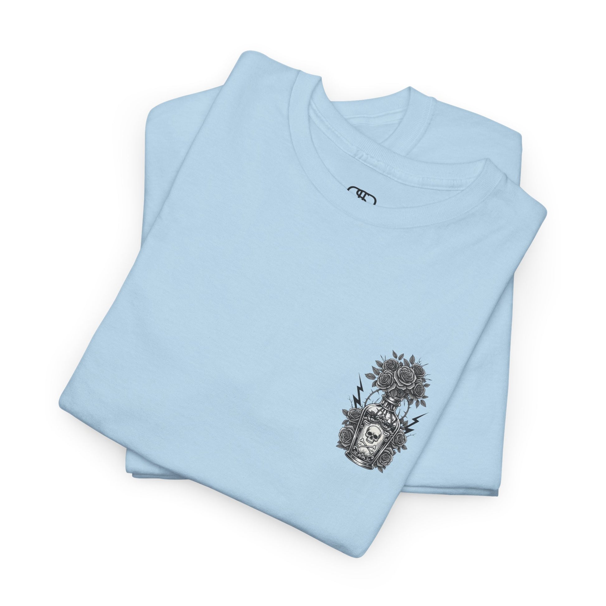 A folded light blue t-shirt with a skull and crossbones vase filled with roses and the words “Surviving Purely Out of Spite” in a gothic font.