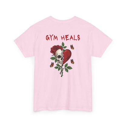 A light pink t-shirt with a front design of a half skull, half broken heart, and a rose. The back reads "Gym Heals" in red.
