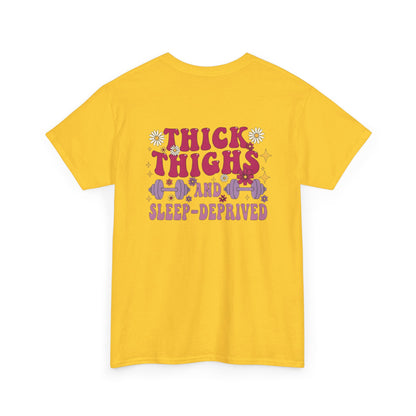 A [daisy] t-shirt with the phrase "Thick Thighs and Sleep Deprived" in a retro font on the front left and enlarged on the back.