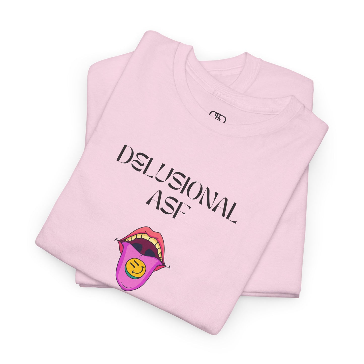 A folded light pink T-shirt with "Delusional asf" text, an open mouth graphic with tongue out, and a happy face emoji pill.