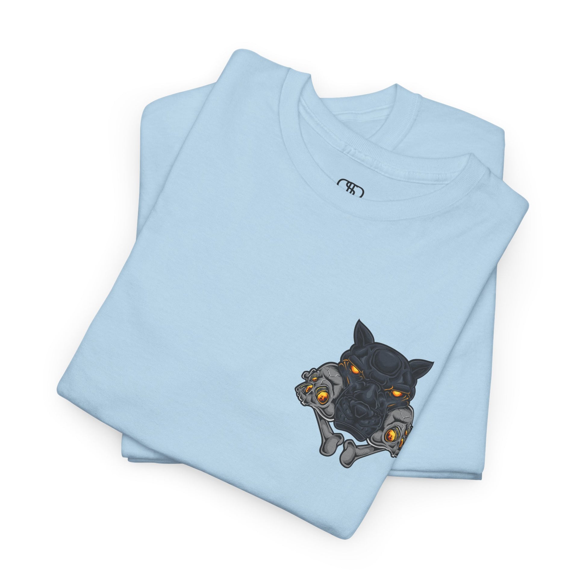 A folded light blue T-shirt with a daring dog graphic biting two skulls, all with glowing molten lava-like eyes.