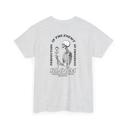 An [Ash gray] t-shirt with a central skeleton and rose design and the words “Perfection is the enemy of progress” and “Bloom” on the front.