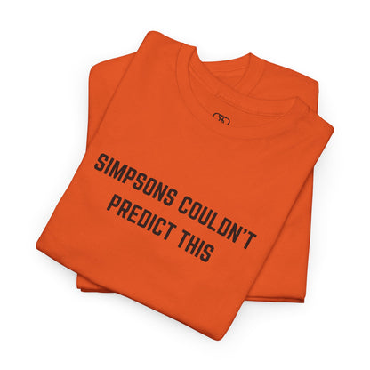 A folded orange T-shirt with the text "Simpsons Couldn't Predict This."

