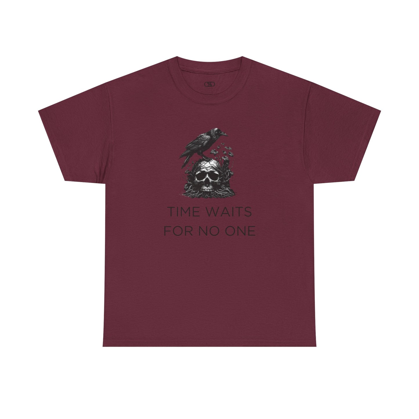 A close-up of a t-shirt with a gothic illustration. A black crow stands atop a weathered skull, which has moss and delicate vines growing through its eye sockets and around its form, blending nature and death.