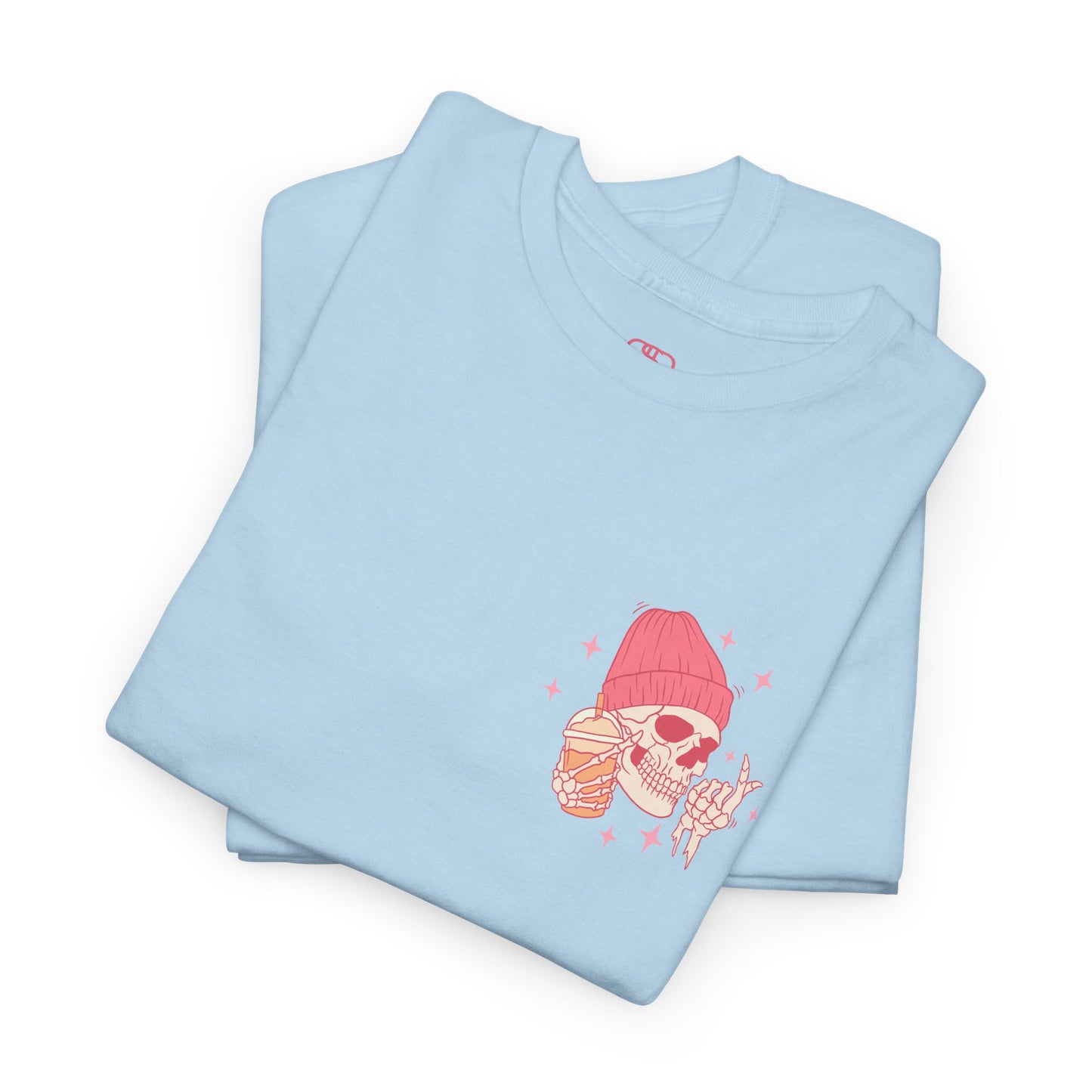 A LIGHT BLUE FOLDED T-shirt with a skeleton in a pink beanie holding a frozen coffee, snapping fingers, surrounded by sparkles graphic.