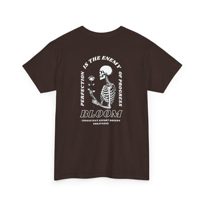 A [dark brown] t-shirt with a central skeleton and rose design and the words “Perfection is the enemy of progress” and “Bloom” on the front.
