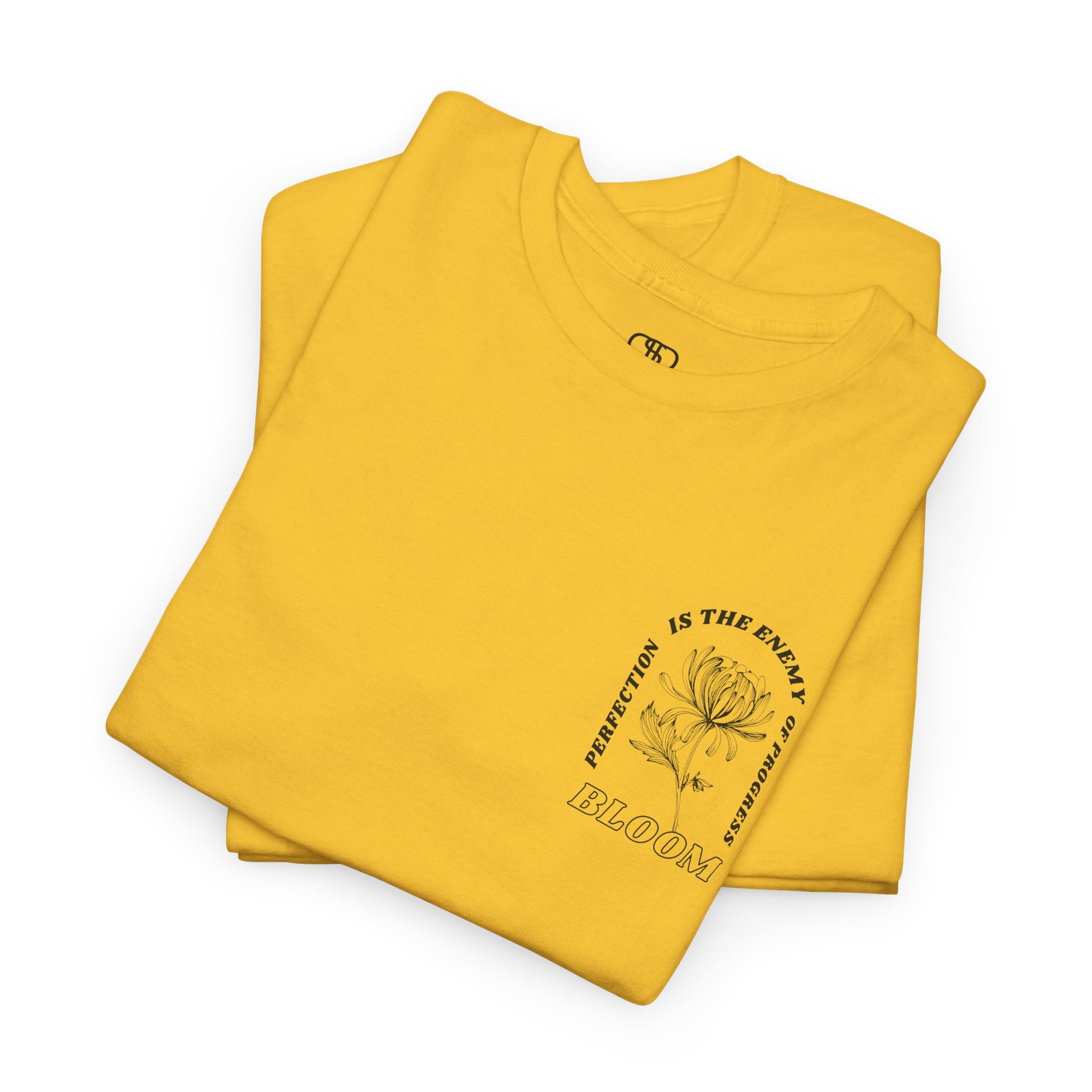 A [folded daisy] t-shirt with a central flower design and the words “Perfection is the enemy of progress” and “Bloom” underneath it the phrase "Consistent effort breeds greatness," featured on the back of the t-shirt.