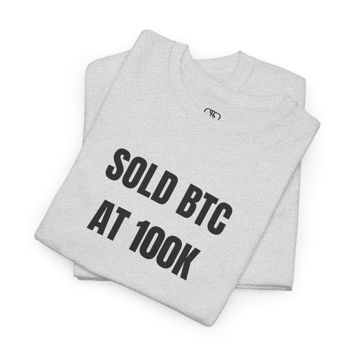 A folded ash gray T-shirt with bold text "SOLD BTC At 100K" on the front.