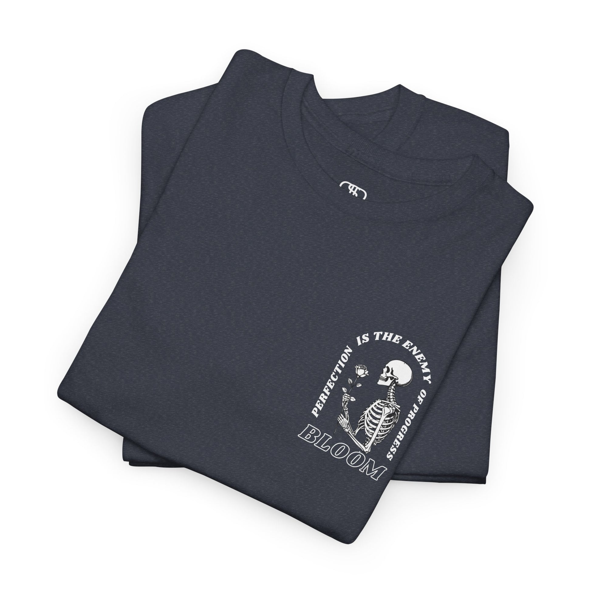A [folded navy] t-shirt with a central skeleton and rose design and the words “Perfection is the enemy of progress” and “Bloom” on the front.