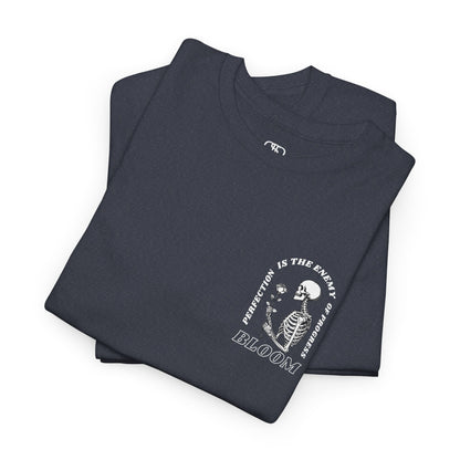 A [folded navy] t-shirt with a central skeleton and rose design and the words “Perfection is the enemy of progress” and “Bloom” on the front.
