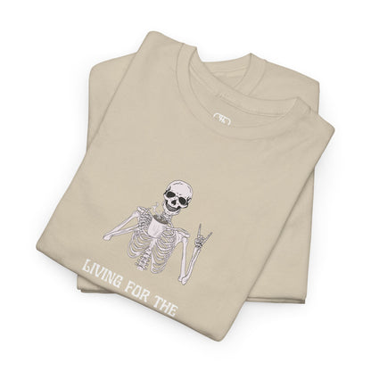 A folded sand T-shirt with a skeleton holding a hot coffee, displaying a rock hand symbol, and "Living For The Coffee" text.
