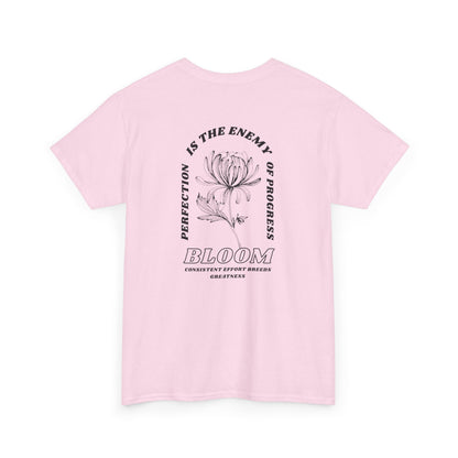 A [light pink] t-shirt with a central flower design and the words “Perfection is the enemy of progress” and “Bloom” underneath it the phrase "Consistent effort breeds greatness," featured on the back of the t-shirt.