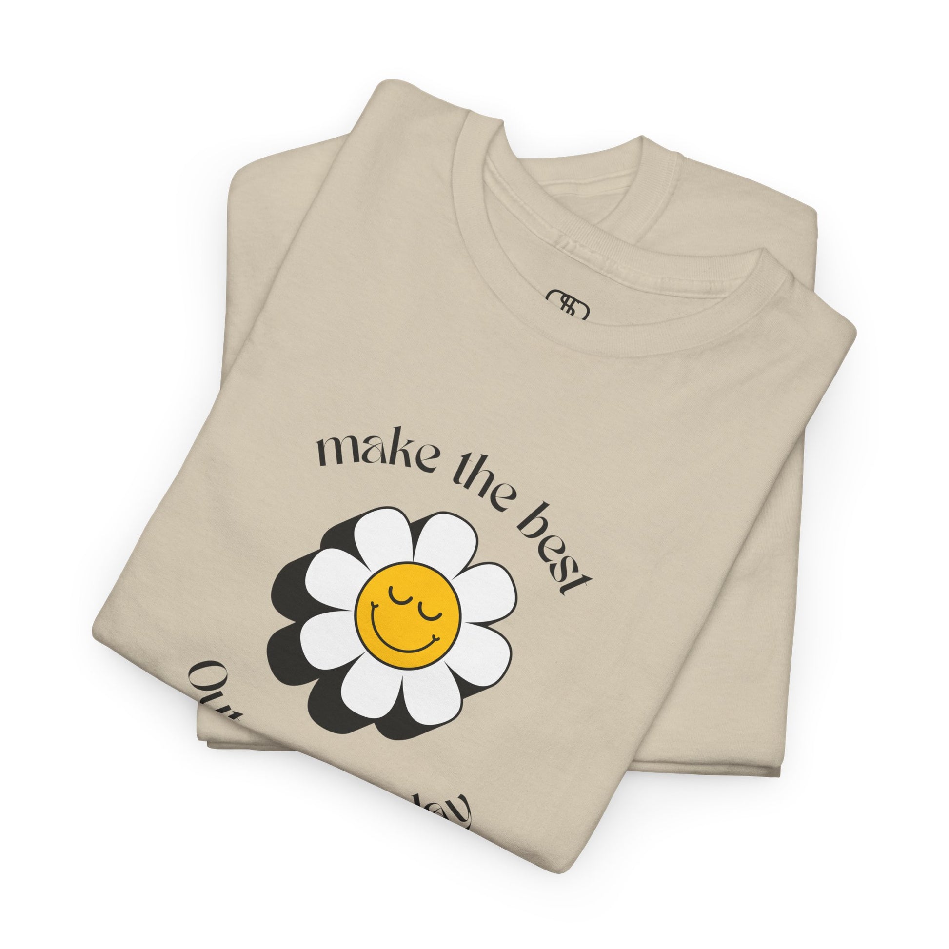A folded sand t-shirt with a smiling sunflower and the words “Make the best out of Everyday” on the front and “Dear Person behind me, I’m glad that you are here” on the back.