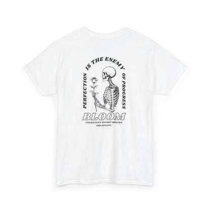 A [white] t-shirt with a central skeleton and rose design and the words “Perfection is the enemy of progress” and “Bloom” on the front.