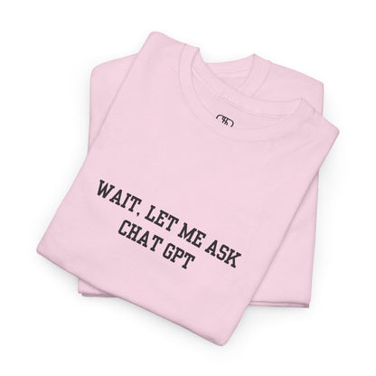 A [folded light pink] t-shirt with the phrase “Wait, Let me ask Chat Gpt.” on the front.
