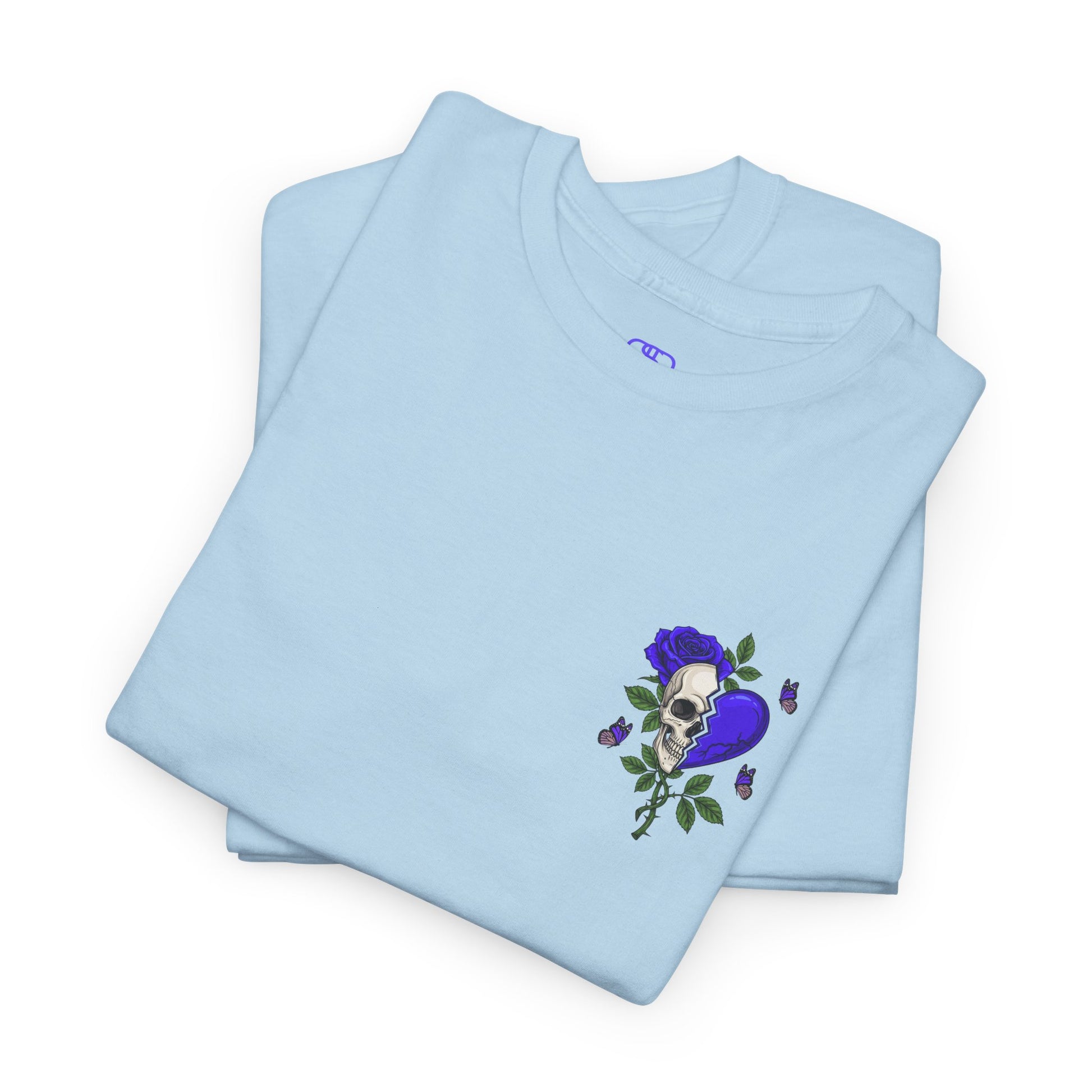 A folded light blue t-shirt with a front design of a half skull, half broken purple heart, and a rose. The back reads "Gym Heals" along with a similar design found on the front.