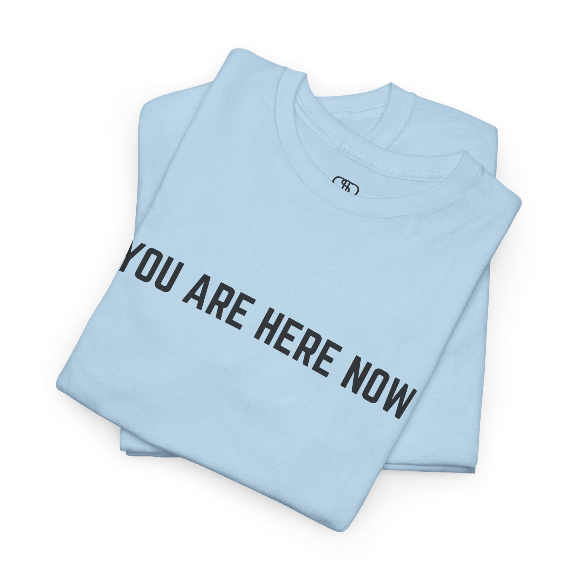 A folded t-shirt with the words "You are Here Now." 
