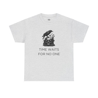 A close-up of a t-shirt with a gothic illustration. A black crow stands atop a weathered skull, which has moss and delicate vines growing through its eye sockets and around its form, blending nature and death.