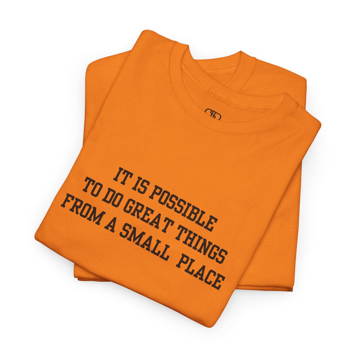 A folded orange t-shirt with the quote “It is possible to do great things from a small place” on the front.