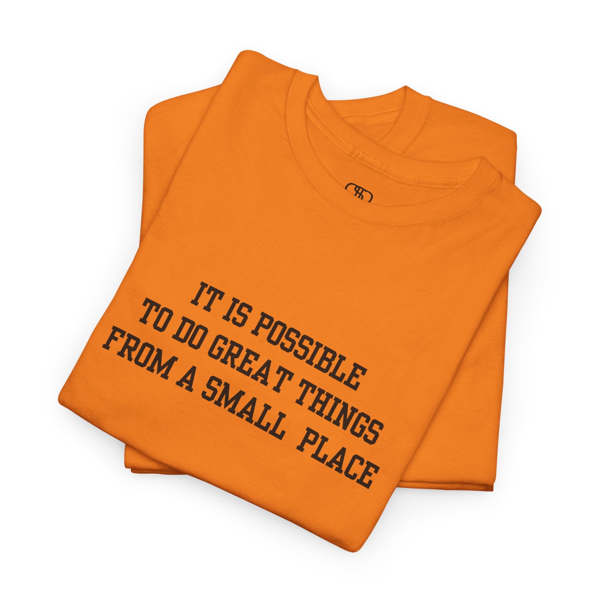 A folded orange t-shirt with the quote “It is possible to do great things from a small place” on the front.