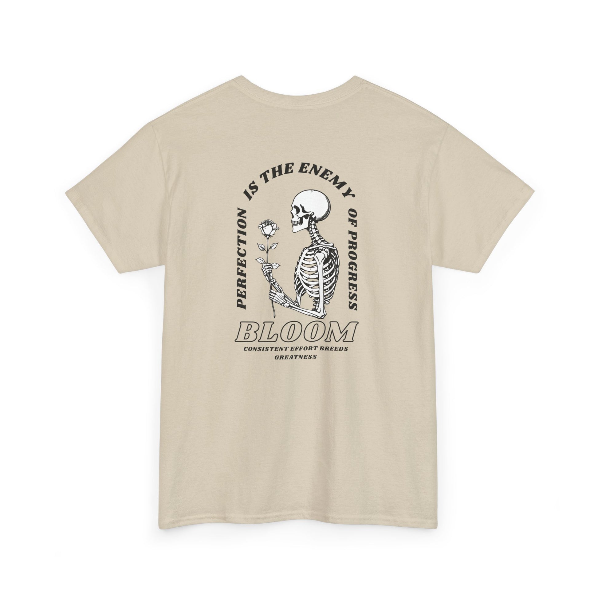 A [sand] t-shirt with a central skeleton and rose design and the words “Perfection is the enemy of progress” and “Bloom” on the front.