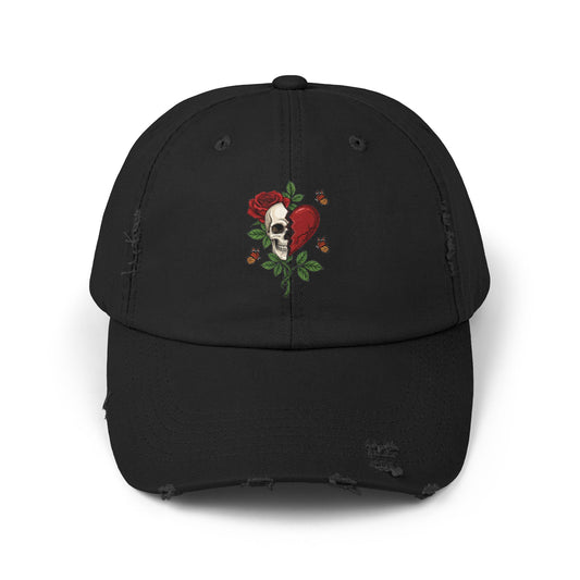 A distressed black hat with an embroidered design of a half-skull and half-heart, split by a tear. A rose grows from the skull, surrounded by thorns and butterflies.