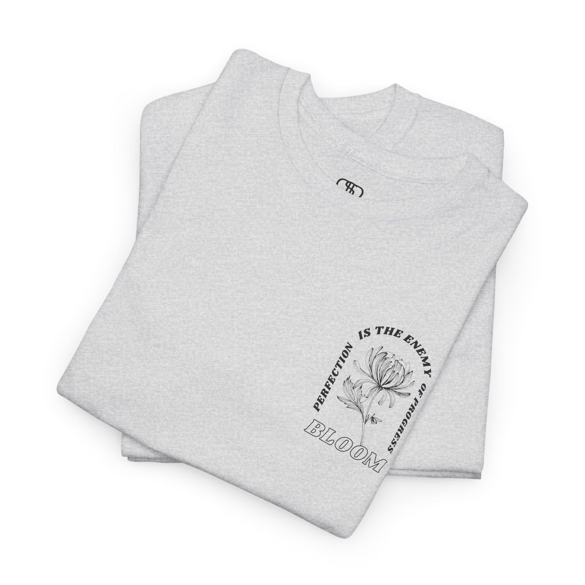 A [folded ash gray] t-shirt with a central flower design and the words “Perfection is the enemy of progress” and “Bloom” underneath it the phrase "Consistent effort breeds greatness," featured on the back of the t-shirt.