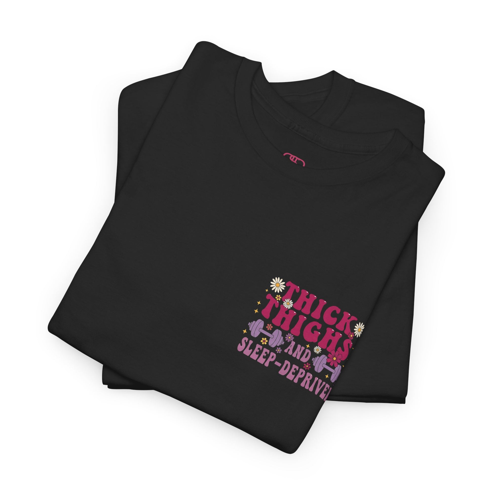 A folded [black] t-shirt with the phrase "Thick Thighs and Sleep Deprived" in a retro font on the front left and enlarged on the back.