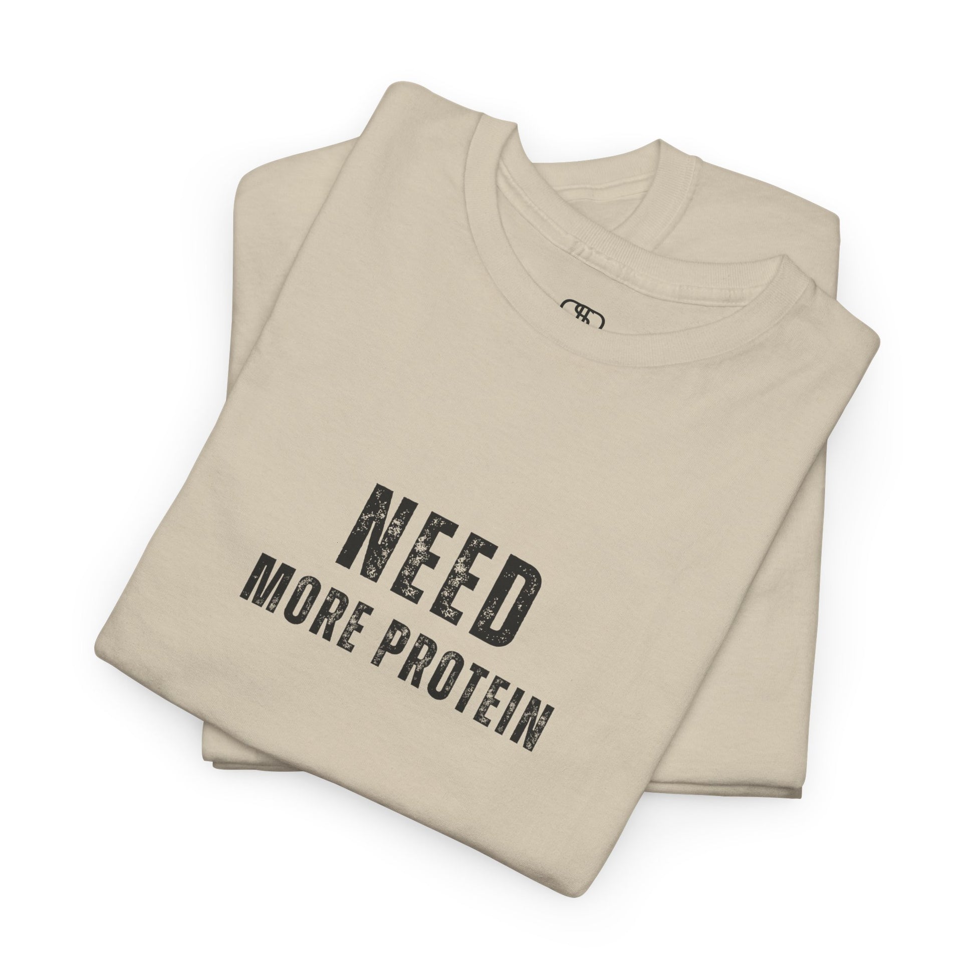 A folded sand t-shirt with the words “Need Protein” in a large grunge font.