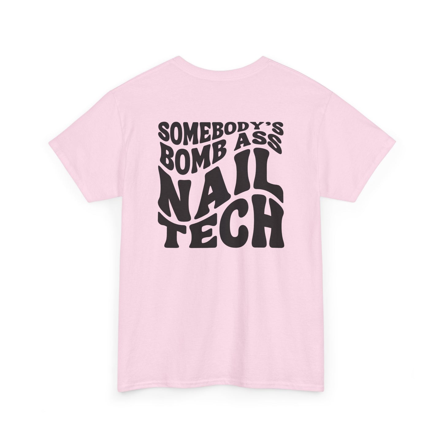 A light pink t-shirt with black text 'SOMEBODY'S BOMB ASS NAIL TECH' on a white background in a creative wavy font. 