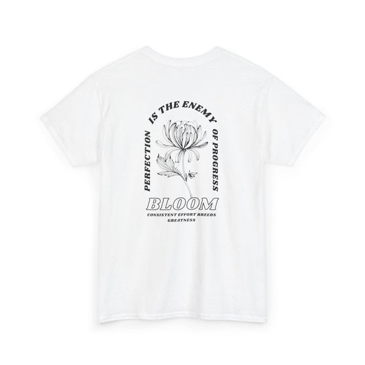 A [white] t-shirt with a central flower design and the words “Perfection is the enemy of progress” and “Bloom” underneath it the phrase "Consistent effort breeds greatness." 