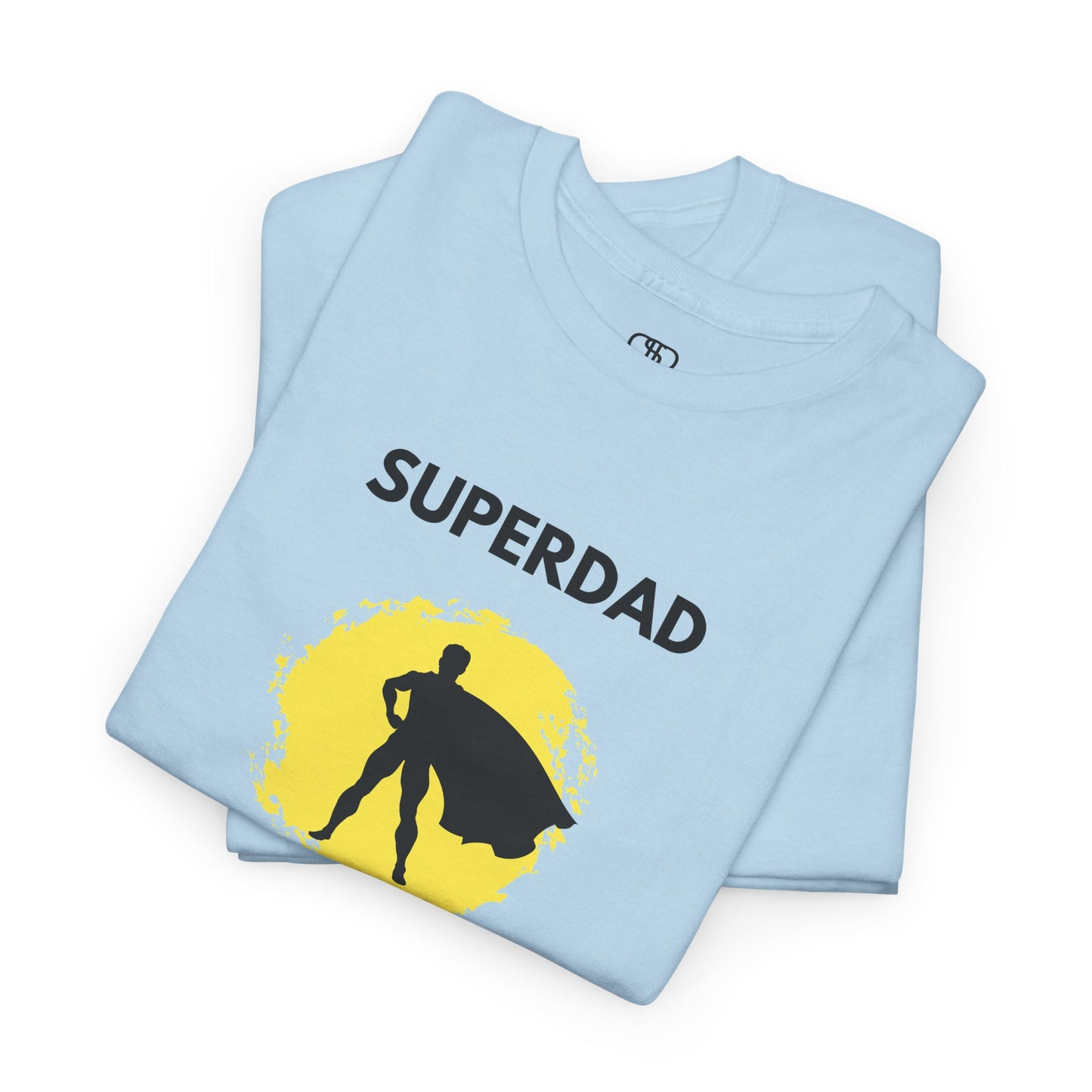 A folded light blue T-shirt with a "Superdad" text and a silhouette of a person with a cape on a yellow circle background.