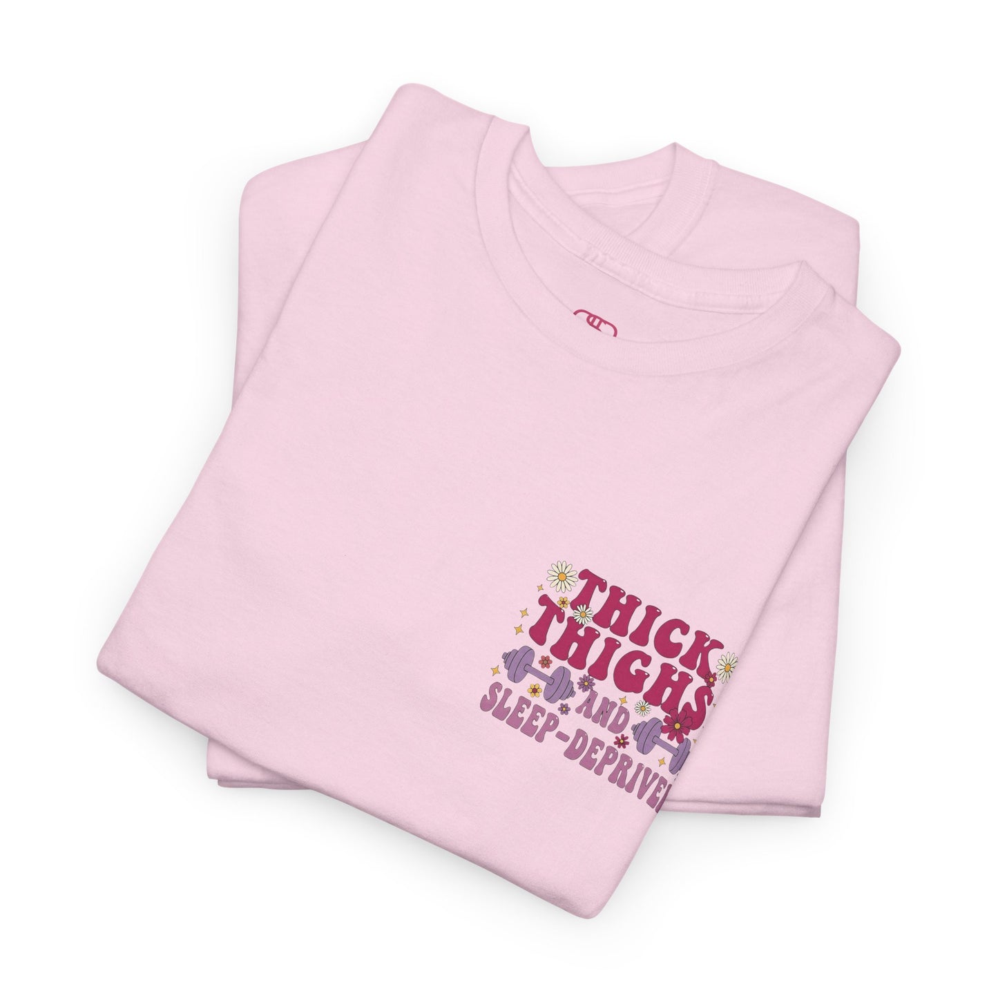 A [light pink] t-shirt with the phrase "Thick Thighs and Sleep Deprived" in a retro font on the front left and enlarged on the back.