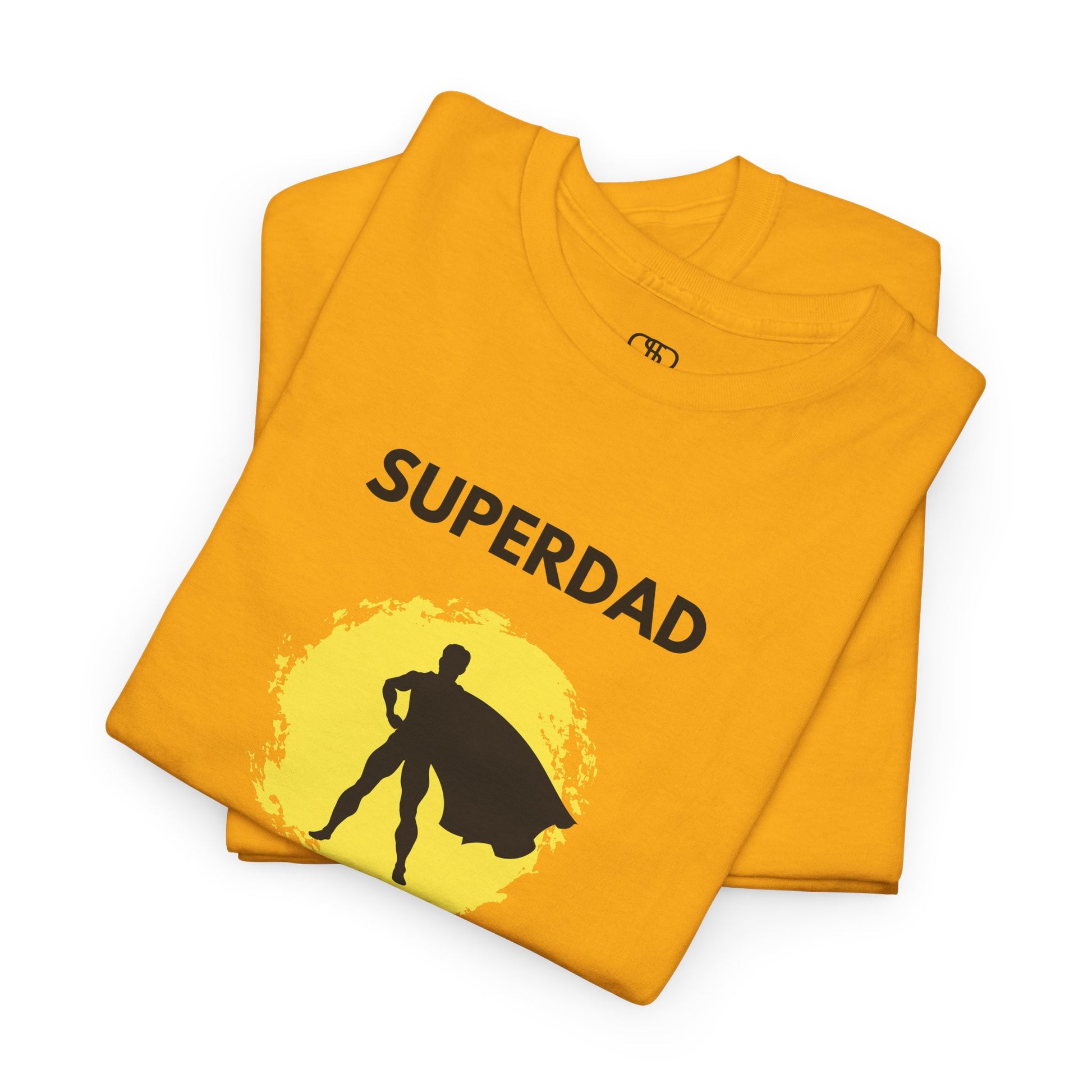 A folded gold  T-shirt with a "Superdad" text and a silhouette of a person with a cape on a yellow circle background.