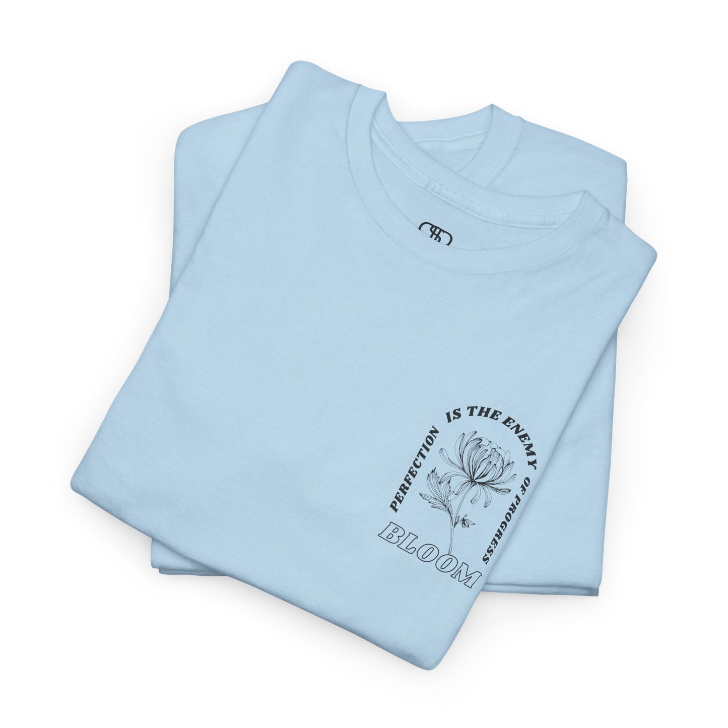 A [folded light blue] t-shirt with a central flower design and the words “Perfection is the enemy of progress” and “Bloom” underneath it the phrase "Consistent effort breeds greatness," featured on the back of the t-shirt.