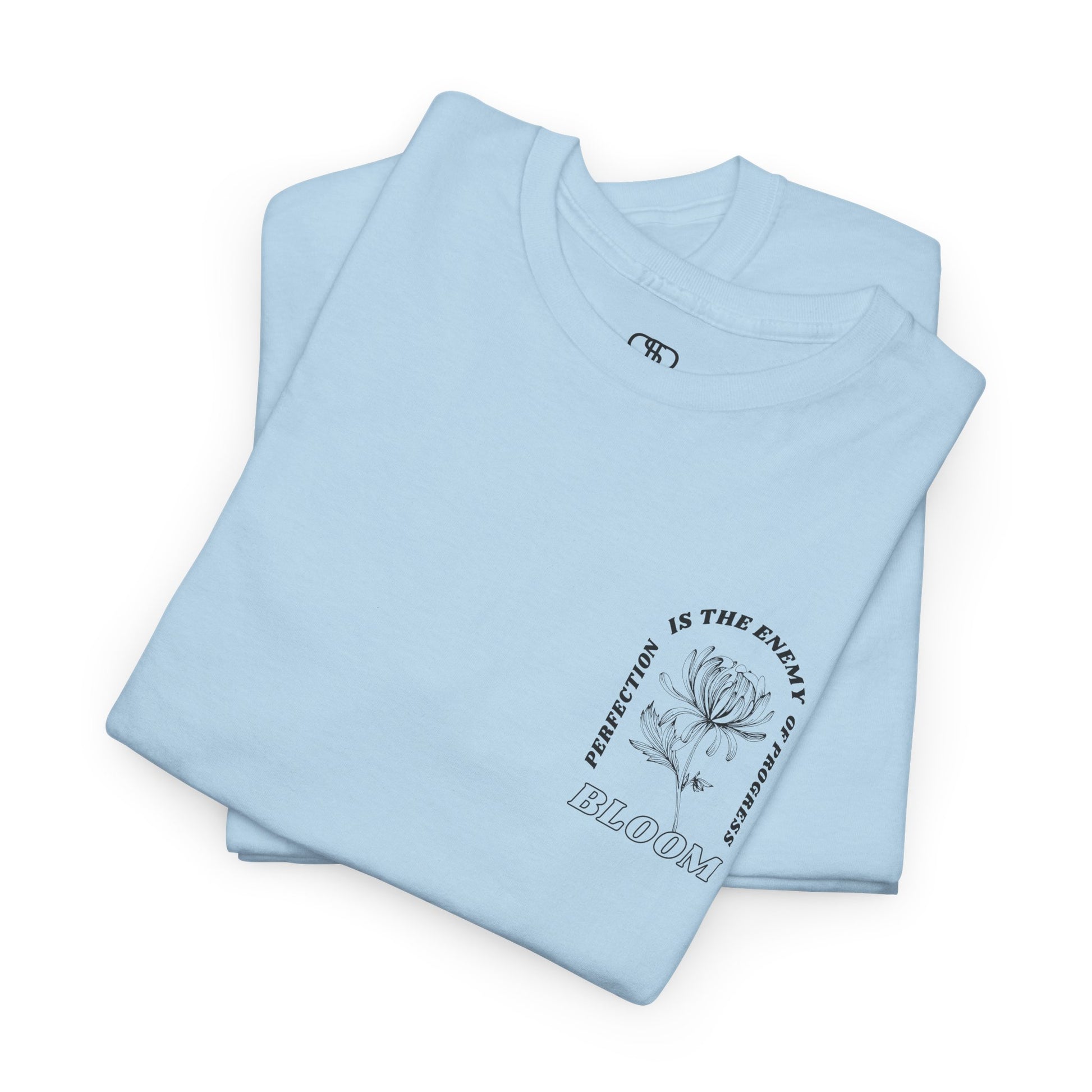 A [folded light blue] t-shirt with a central flower design and the words “Perfection is the enemy of progress” and “Bloom” underneath it the phrase "Consistent effort breeds greatness," featured on the back of the t-shirt.