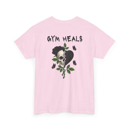 A light pink t-shirt with a front design of a half skull, half broken heart, and a rose. The back reads "Gym Heals" in black.